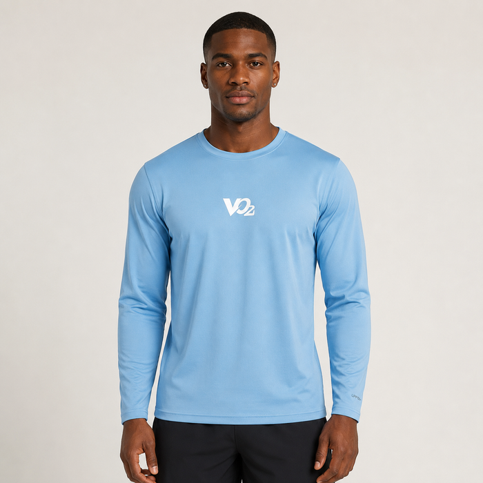 A man wearing a light blue long-sleeve athletic shirt with a white VO2 logo on the chest, paired with black pants, standing against a light gray studio background.